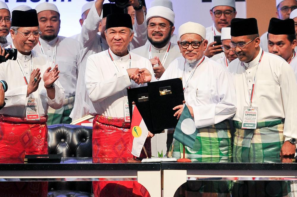 Umno president Datuk Seri Ahmad Zahid Hamidi (3rd L) and PAS president Abdul Hadi Awang (2ndR) exchange documents following the signing of a charter to formalise the political cooperation between the two parties, on Sept 14, 2019. — Bernama