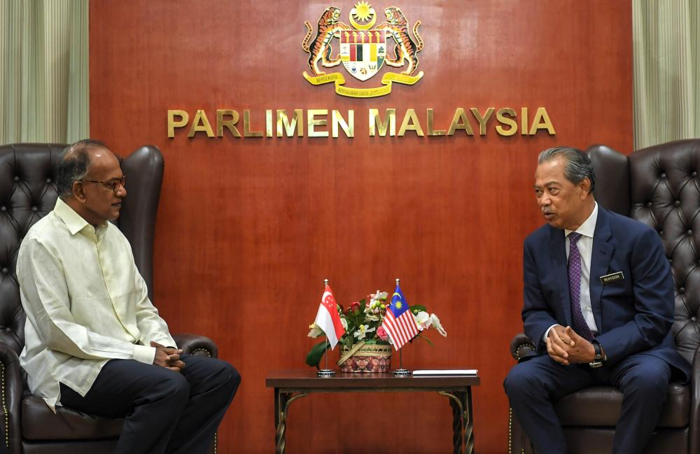 Home Minister Tan Sri Muhyiddin Yassin (R) talked with his colleague Singapore Law and Home Minister K. Shanmugam at Parliament yesterday. - Bernama