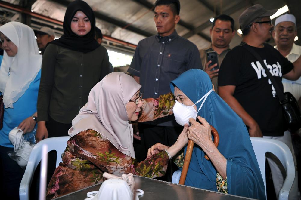 Deputy Prime Minister Datuk Seri Dr Wan Azizah Wan Ismail (seated left) helps fit the N95 face mask, on senior citizen Aishah Hussin (seated right), after handing out 1,200 N95 face masks to the public, courtesy of the Pandan Service Centre, at the Taman Nirwana Muhibah Complex, on Sept 21, 2019. — Bernama