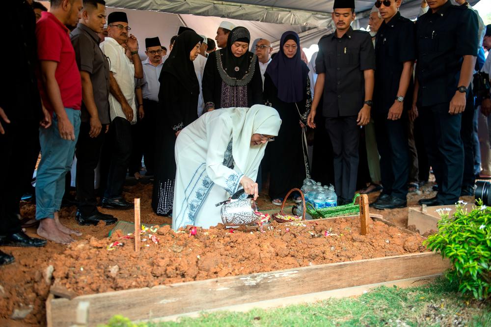 Deputy Prime Minister Datuk Seri Dr Wan Azizah Wan Ismail sprinkles roses at the grave of her father Dr Wan Ismail Wan Mahmood, 93, at the Ukay Perdana Muslim Cemetery in Ampang today. - Bernama