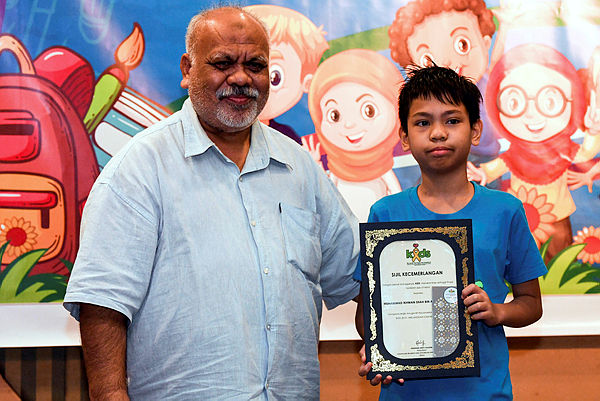 Muhammad Ikhwan Shah Aries Iskandar, 12, (right) receives his award for excellence in education at the ‘Back to School KIDS’ programme in Kuala Lumpur yesterday. — Bernama