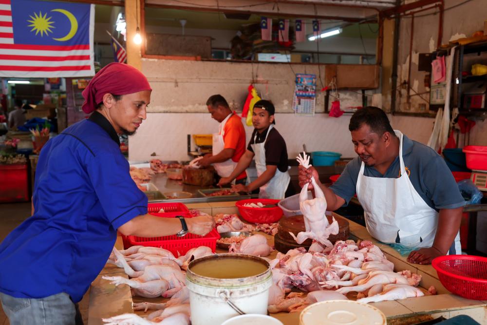 Peniaga melayan pelanggan yang ingin membeli ayam di gerai mereka ketika tinjauan di Pasar Sungai Besi pada Dis 29 2022. - BERNAMA