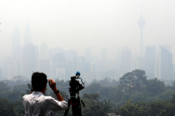 A cameraman taking a video of the thick haze covering Kuala Lumpur today. — Bernama