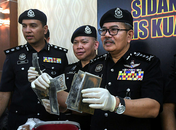 Kuala Lumpur police chief Commissioner Datuk Seri Mazlan Lazim reveals the items seized during a press conference on a ‘black money’ fraud syndicate at the Kuala Lumpur police headquarters today. — Bernama