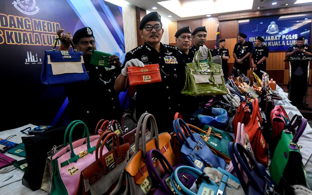 Kuala Lumpur police chief Datuk Seri Mazlan Lazim (c) displays the luxury brand handbags that were seized at a press conference, at the Kuala Lumpur police headquarters today. - Bernama