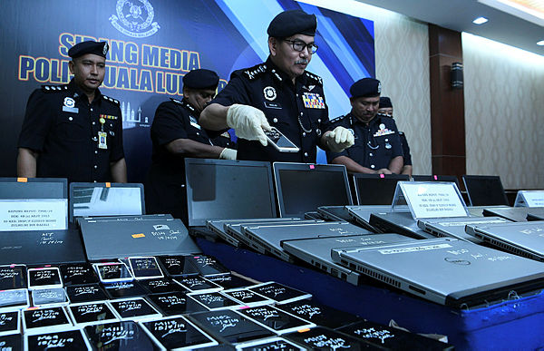 City police chief Datuk Seri Mazlan Lazim inspecting a portion of the seized good at a press conference in the Kuala Lumpur Police Contingent Headquartes today.