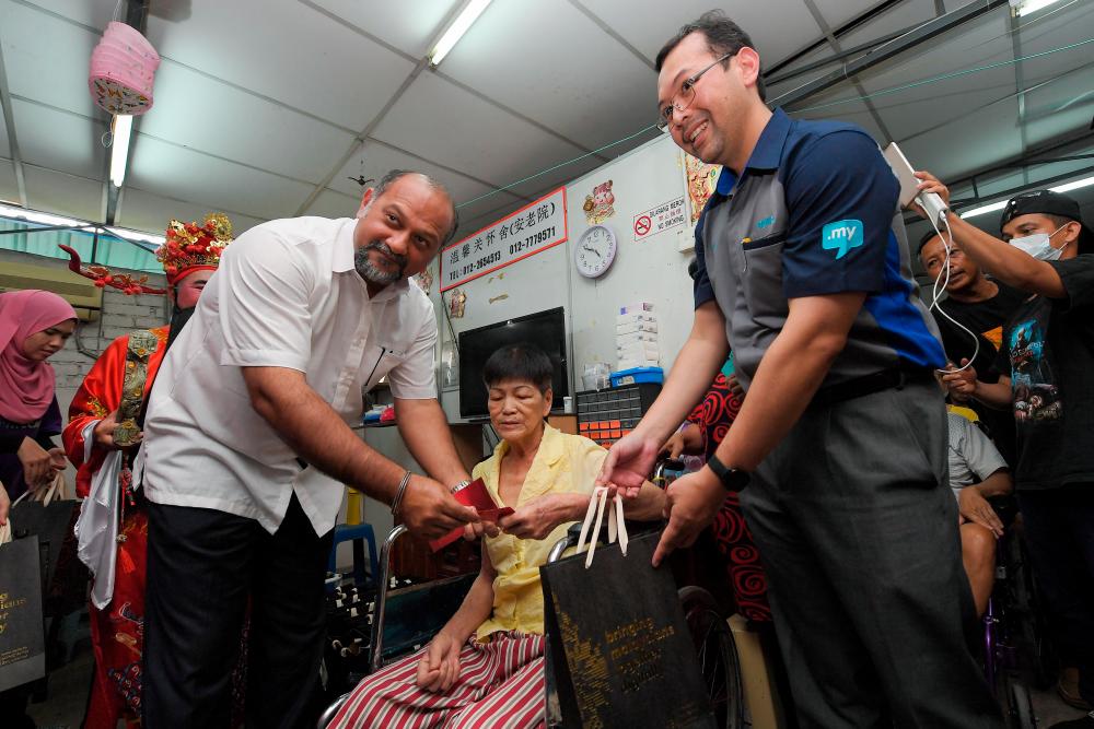 Communications and Multimedia Minister Gobind Singh Deo (L) and MYNIC CEO Hasnul Fadhly Hasan (R) present contributions to some of the members of the Pusat Jagaan Orang Tua Wan Hing as part of the #MYNICCARES programme. - Bernama
