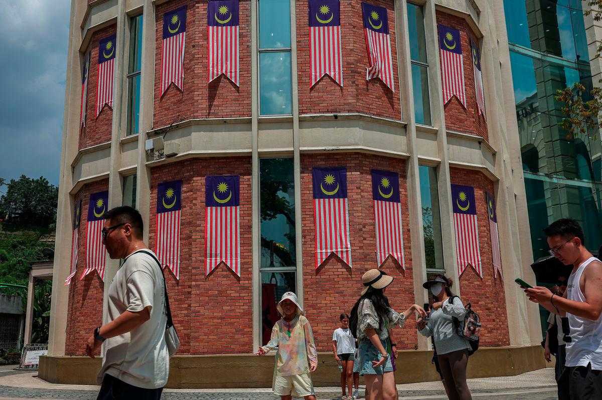 Foreign tourists stroll around Dataran Merdeka with buildings adorned with the Jalur Gemilang in the background, ahead of the National Day and Malaysia Day (HKHM) 2025 celebrations. – BERNAMA