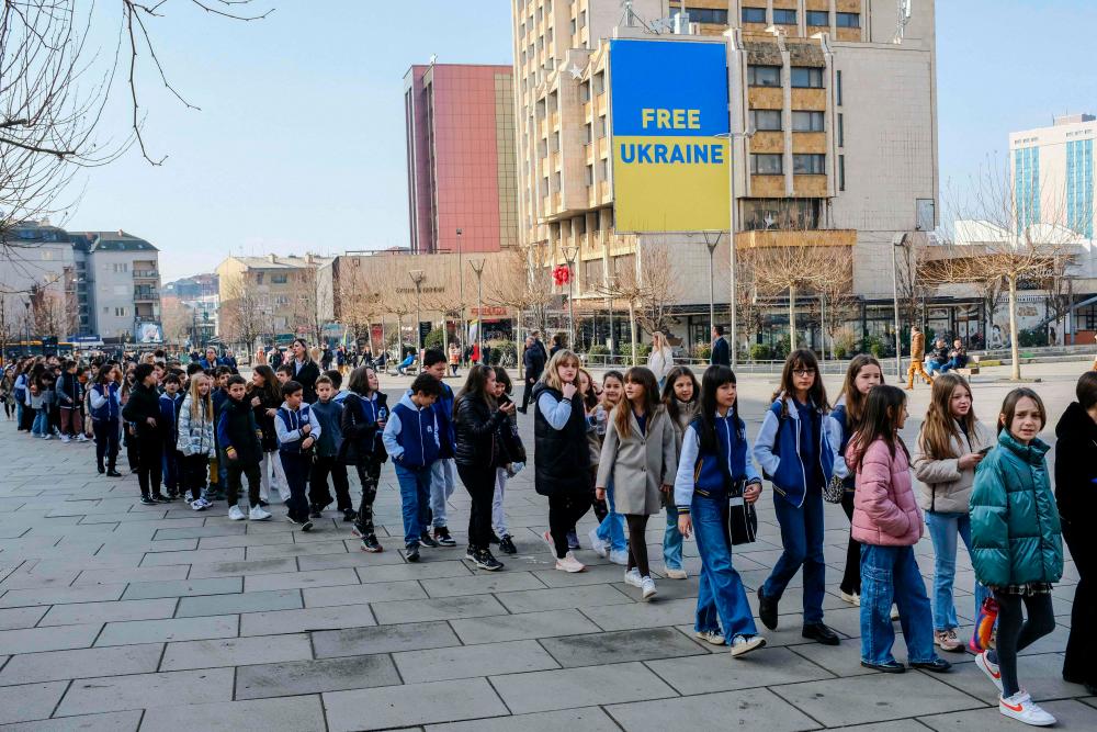 Kosovo Albanian pupils walk past a giant banner showing Ukrainian flag with the words “Free Ukraine” displayed in the main square in Pristina on February 24, 2023 to mark the one year anniversary of the Russian invasion of Ukraine. AFPPIX