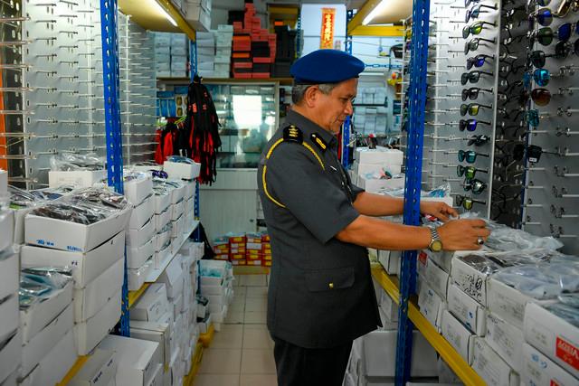 One of the ministry enforcement officer checking on the seized counterfeit eyewear items.-Bernama