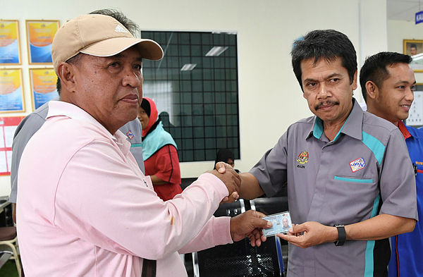 JPN director-general Datuk Muhammad Razin Abdullah (2R) handing replacement documents to a Kudat victim. — Bernama