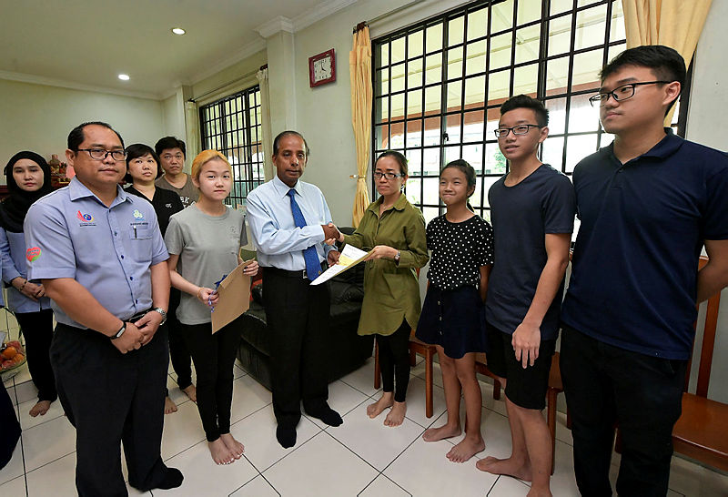 Human Resources Minister, M. Kula Segaran (3rd L) presents a cheque for RM2,000 to Lo Kok Ping, 47 (4th R), a family member of the victim of a gas explosion in Cityone Megamall, in the form of funeral benefit payment, on Dec 13, 2018. — Bernama