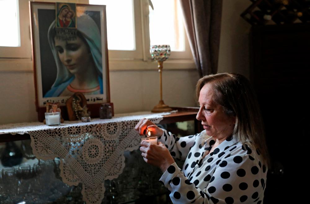 Civil war survivor Abla Barotta, 58, lights a candle to place on a small shrine in her home in Lebanon’s capital Beirut, on April 6, 2021.-AFP