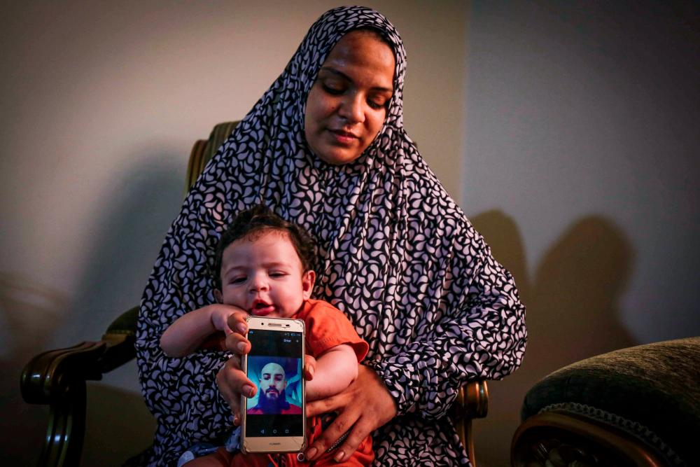 Suad Mohammad, 27, the wife of Syrian migrant Shady Ramadan who disappeared at sea while undertaking an illicit sea crossing to Cyprus, holds a phone showing her husban’s picture as she sits with her children at her parents’ house in the Qubbeh neighbourhood of Lebanon’s northern port city of Tripoli on Sept 15, 2020. — AFP