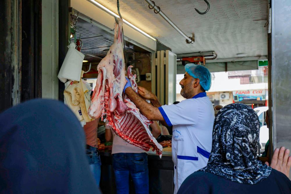 A picture taken on July 28, 2020, shows people waiting for their orders at a butcher in Lebanon’s northern port city of Tripoli, as Muslims across the world are getting ready to celebrate Eid al-Adha. — AFP