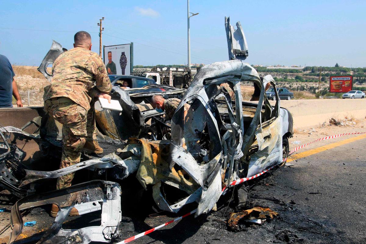 Lebanese army soldiers check the wreckage of a vehicle that was reportedly targeted by an Israeli strike, on the highway near the village of Ansarieyh, south of the coastal city of Sidon on August 8, 2025. Photo by Mahmoud ZAYYAT / AFP