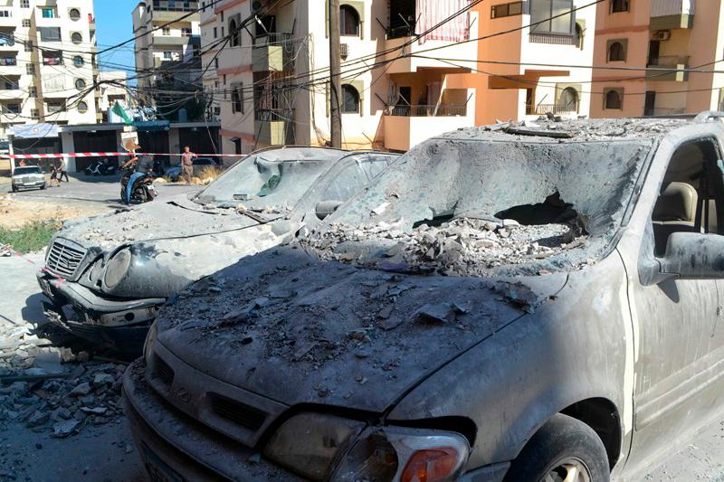 Damaged cars lie in a cordoned-off area hit in an Israeli airstrike that targeted an apartment building in the Palestinian refugees camp of Al-Baddawi near the northern Lebanese city of Tripoli on October 5, 2024. Palestinian militant group Hamas said an Israeli strike killed one of its commanders, Saeed Attallah Ali, his wife and two daughters, in the refugee camp on October 5, the first time the area had been hit since the start of the Gaza war. - FATHI AL MASRI / AFP