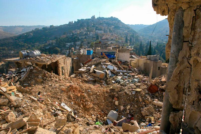 This picture shows a crater and destroyed buildings in the southern Lebanese village of Khirbet Selm near the border with northern Israel on December 3, 2024. A fragile ceasefire took effect on November 27, ending more than a year of war between Israel and Hezbollah that has killed thousands in Lebanon and caused mass displacements on both sides of the border. - Mahmoud ZAYYAT / AFP