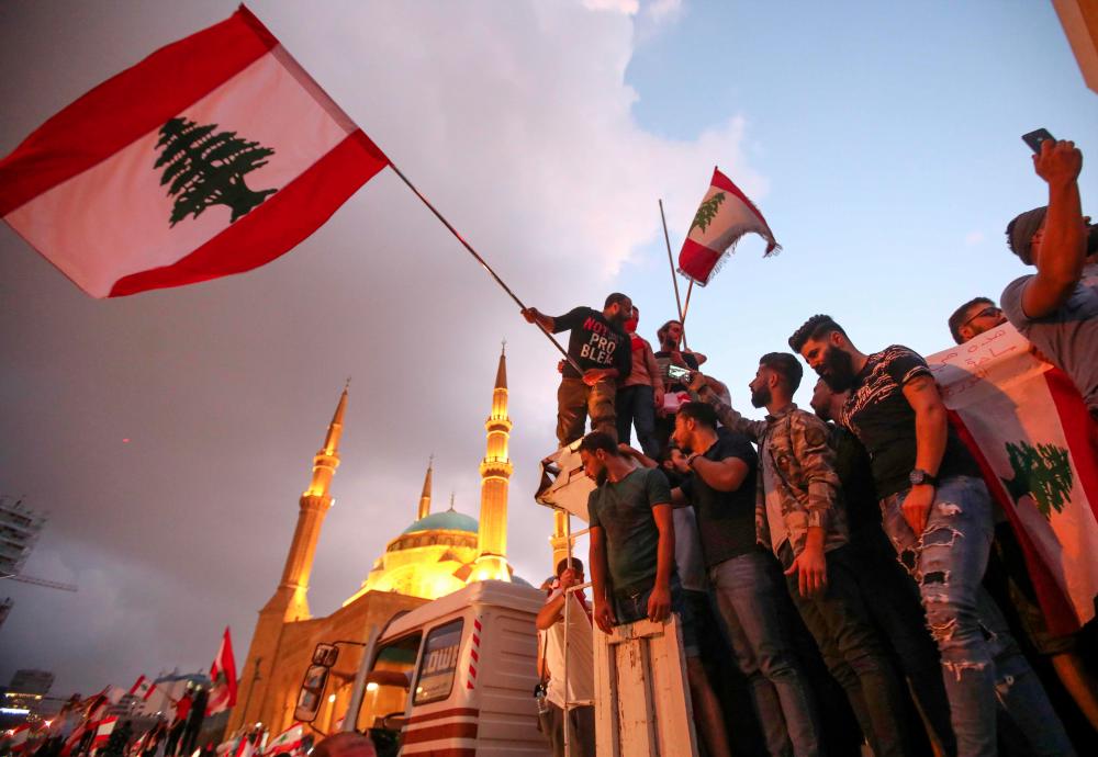 Lebanese demonstrators wave national flags as they take part in a rally in the capital Beirut's downtown district on Oct 20, 2019. — AFP