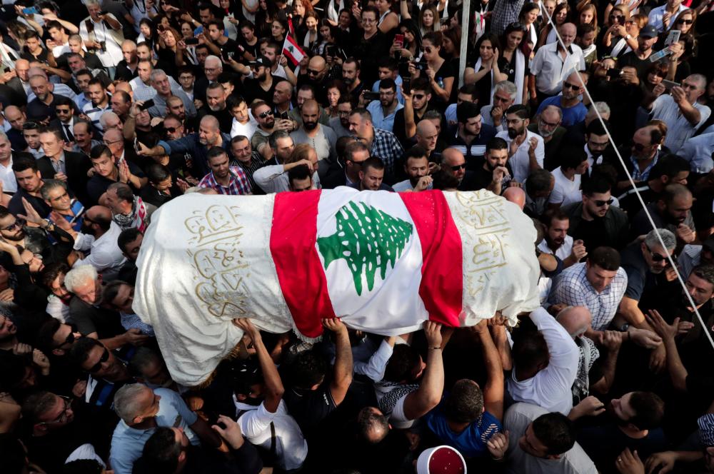 The coffin of slain Lebanese protester Alaa Abou Fakhr, draped in a national flag, is carried by mourners through the streets of his hometown of Chouaifet, southeast of Beirut, during his funeral procession on Nov 14. — AFP