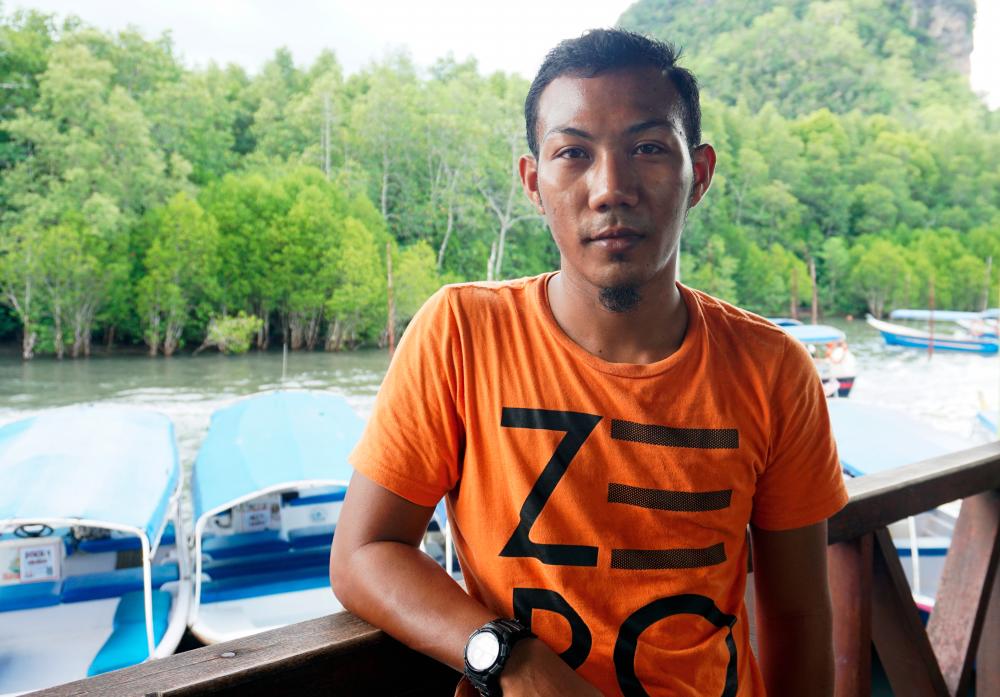 Tourist boat driver Afiq Ali, 27, managed to save the life of a stalled dolphin tied to a stick in an incident at Sungai Kilim, Langkawi on Thursday. - Bernama