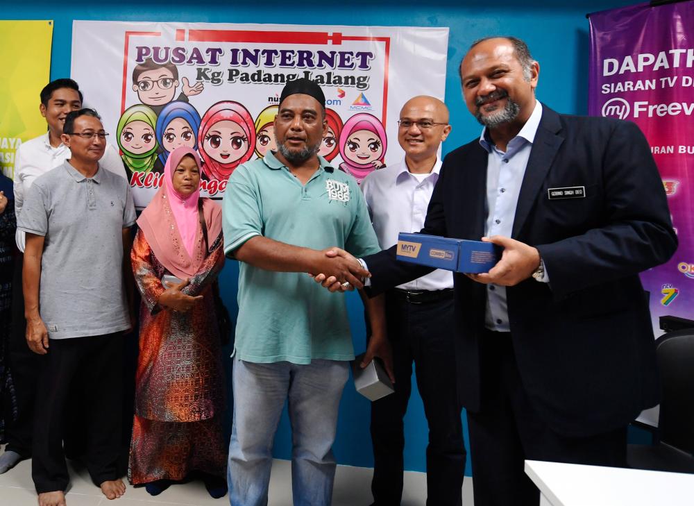 Communications and Multimedia Minister Gobind Singh Deo presents DVB-T2 decoders to six eligible recipients at the Internet centre of Kampung Padang Lalang in Mukim Ayer Hangat, Langkawi today. - Bernama