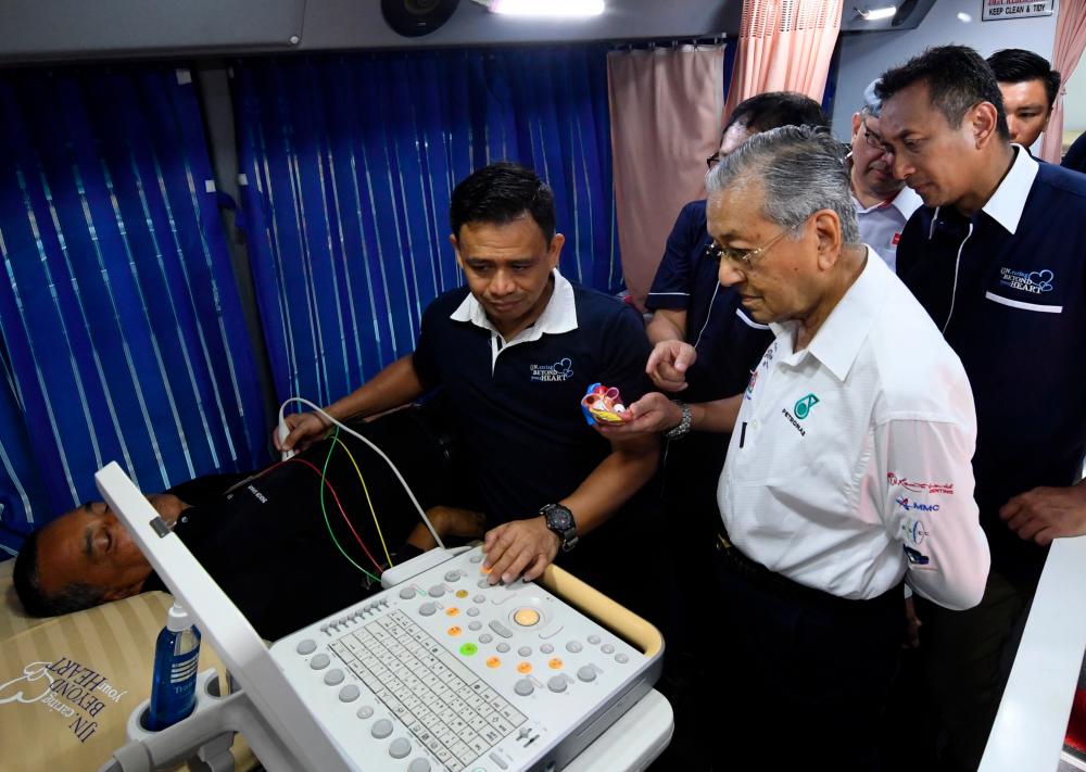 Prime Minister Tun Dr Mahathir Mohamad watching a local taking a health test at the IJN and Media Prima public service programme at Masjid Sungai Itau, Air Hangat today. — Bernama