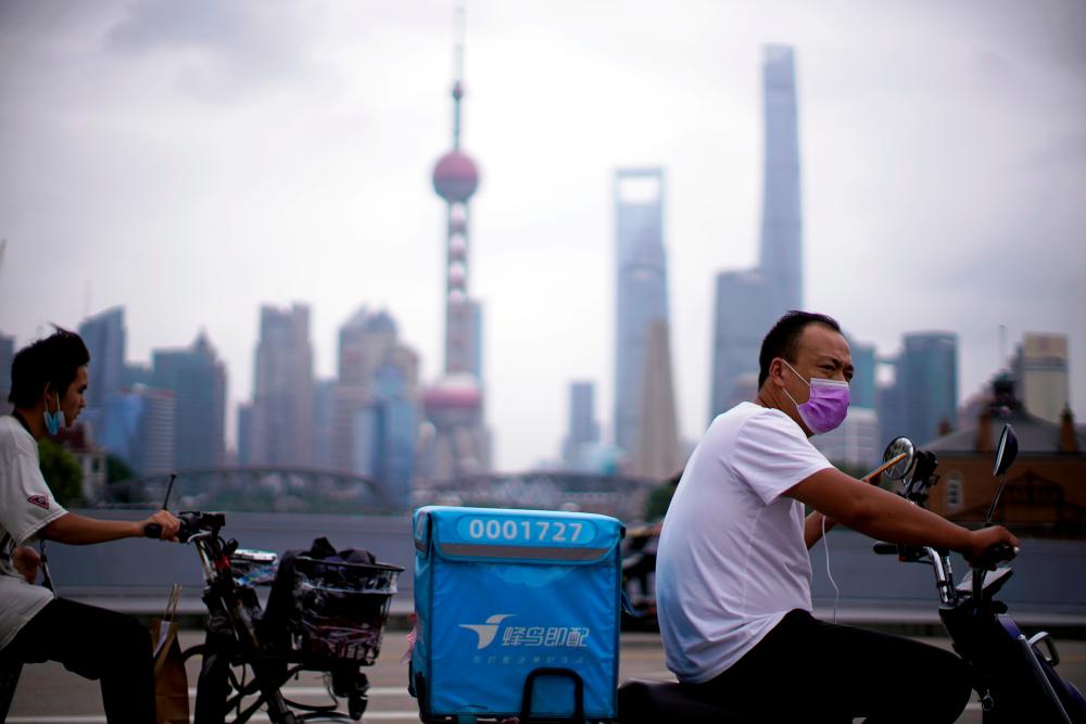 Delivery workers wearing face masks ride scooters in front of Lujiazui financial district, in Shanghai, China. Consumer behaviour changes will have an uncertain impact on the economy, says Moody's Investor Service. – REUTERSPIX