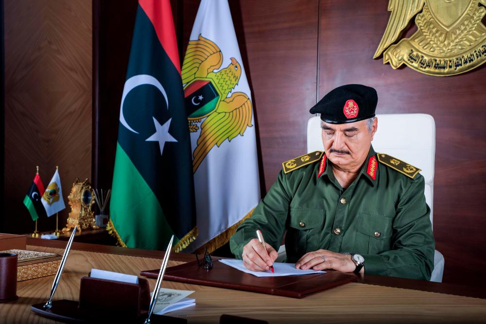 A handout picture released by the Media Office of the Libyan National Army (ANL) General Command on Sept 18, 2020, shows Libyan General Khalifa Haftar writing on a paper at his desk in Benghazi. — AFP