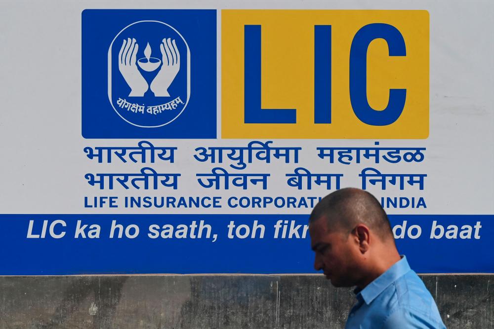 A man walking past a promotional poster of state-owned insurance group and investment company Life Insurance Corporation in Mumbai. AFPpix