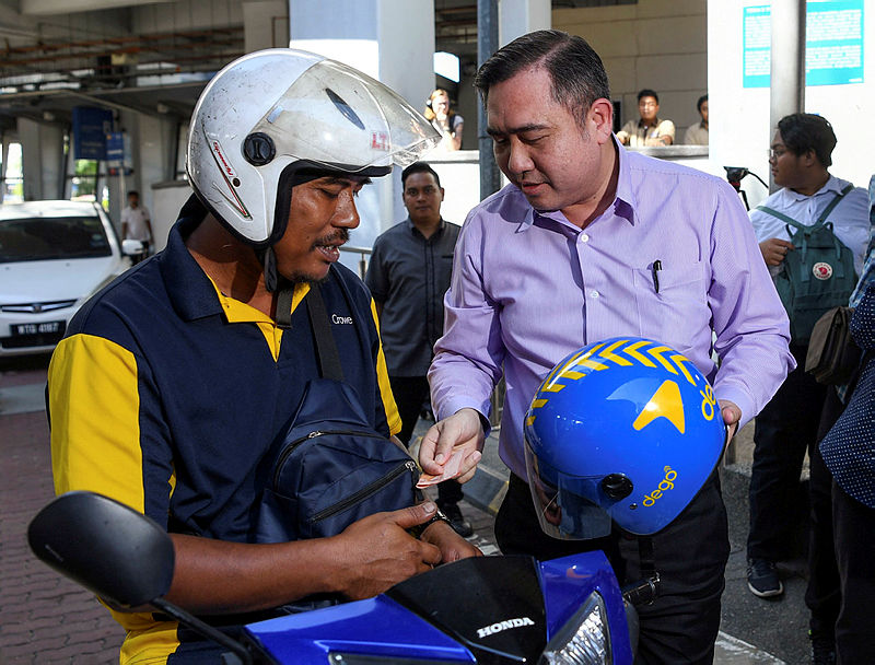 Transport Minister Anthony Loke pays for a ride he took on, with Dego Ride at the city centre, on Jan 6, 2020. — Bernama
