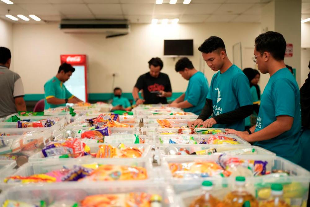 Volunteers from Lotus’s Malaysia and Coca-Cola packing food boxes for families in need.