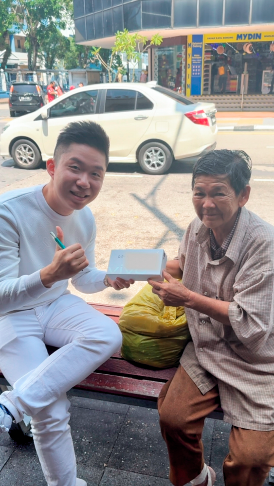 Luo presenting a RM600 smartphone to a senior citizen and teaching her how to use it. $!Luo presenting a RM600 smartphone to a senior citizen and teaching her how to use it.