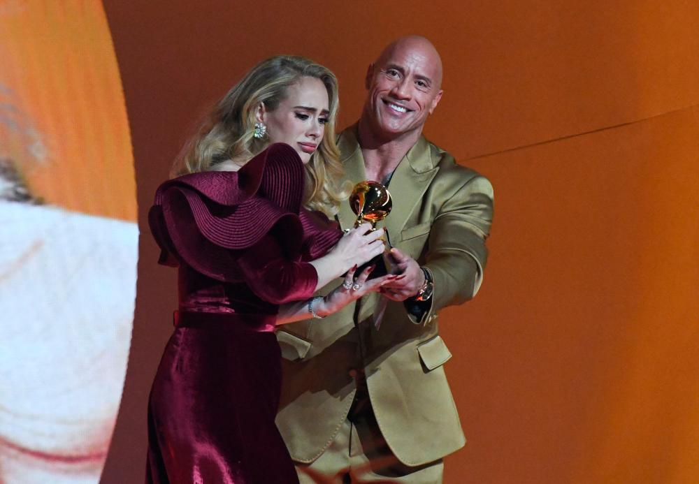 Dwayne Johnson (right) presenting Adele with her award. – AFP