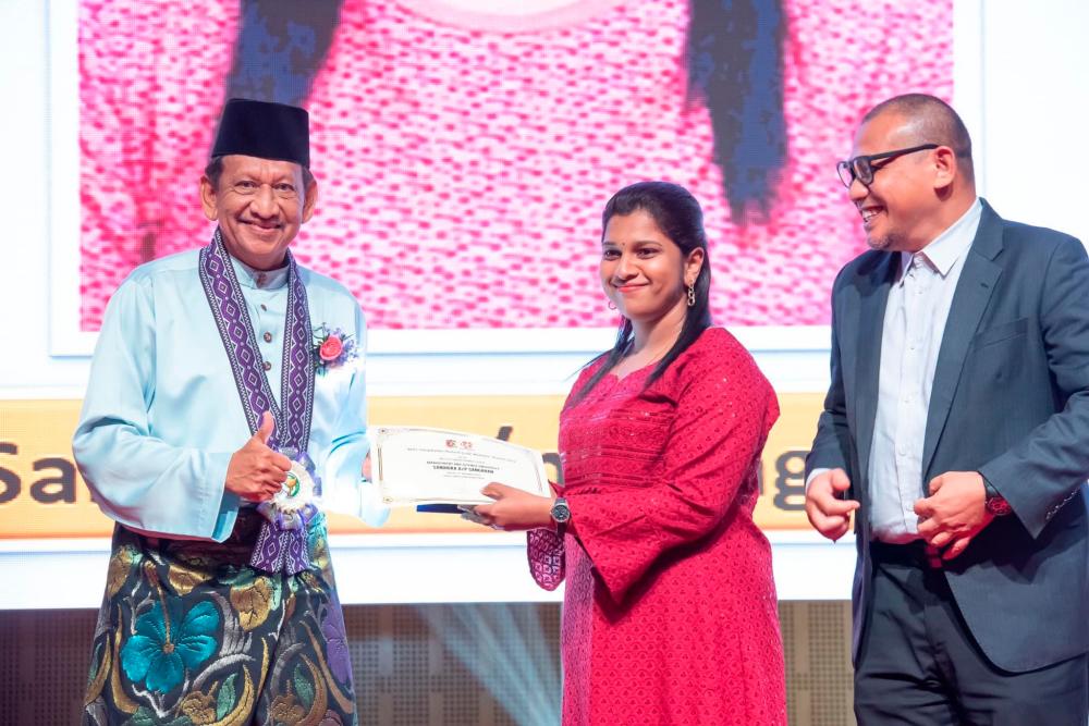 (L-R) MPS President Amrahi Buang presenting Sandrika her award as MSU’s School of Pharmacy, Associate Professor Dr Mohd Fadli Mohd Asmani cheers her on.