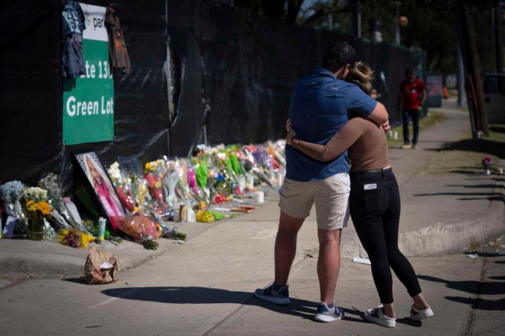 Mourners comfort each other at a memorial outside the concert venue in Houston. - AP