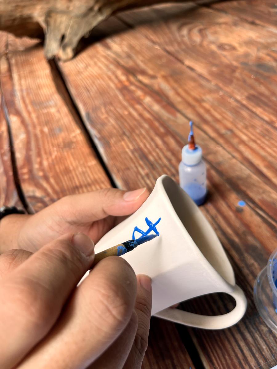 A participant writing her thoughts on a clay cup. $!A participant writing her thoughts on a clay cup.