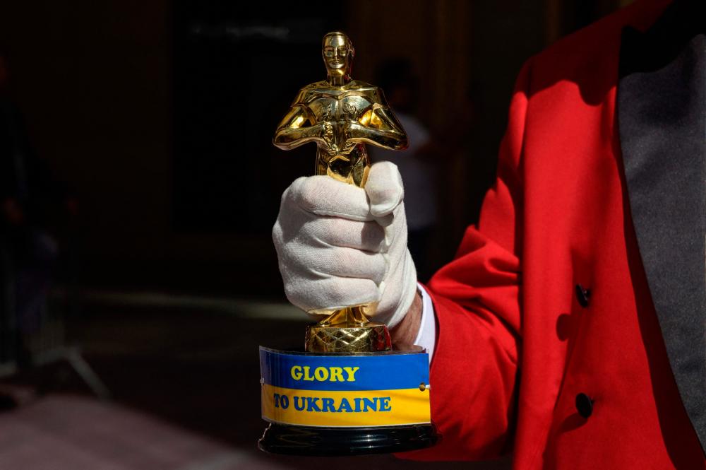 An Oscar statue with a sign reading 'Glory To Ukraine' on display ahead of the Oscars Award show. – AFP