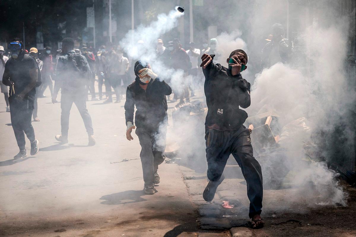 A protester throws a teargas canister back at police officers during clashes with Malagasy security forces during a strike calling for constitutional reforms and the resignation of President Andry Rajoelina, in Antananarivo, on October 9, 2025. - Luis TATO / AFP