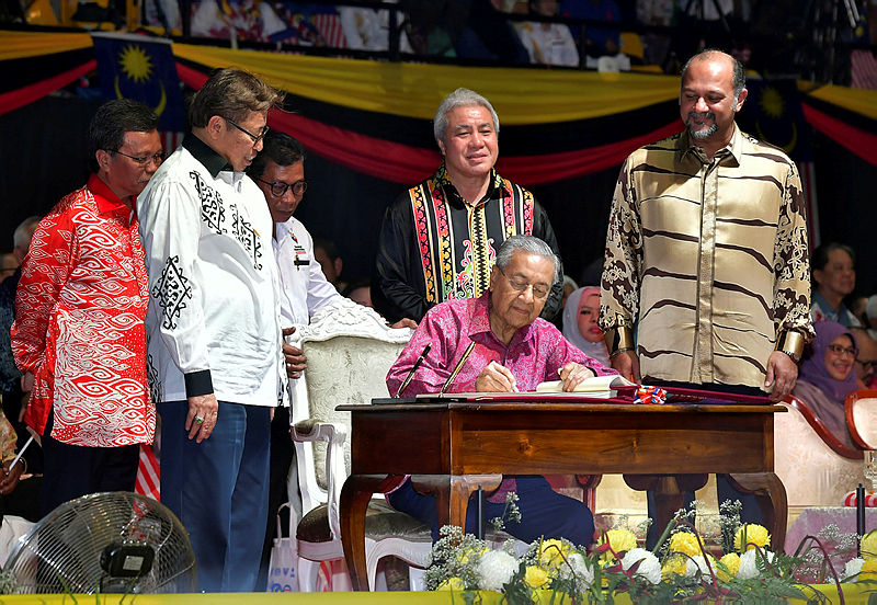 Prime Minister Tun Dr Mahathir Mohamad signs a Malaysia Day commemorative book as Sabah Chief Minister Datuk Seri Mohd Shafie Apdal (L), Sarawak Chief Minister Datuk Patinggi Abang Johari Tun Openg (2ndL), and Communications and Multimedia Minister Gobind Singh Deo (R) look on during the Malaysia Day 2019 celebration at Stadium Perpaduan, Petra Jaya, on Sept 16, 2019. — Bernama