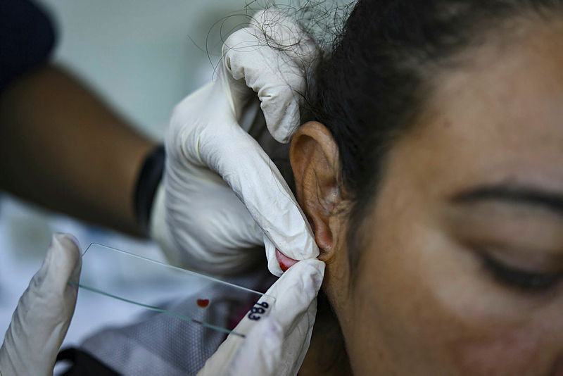 A Venezuelan Health official performs a blood test on a woman at the Central University of Venezuela’s Center for Malaria Studies in Caracas on April 29, 2019. — AFP