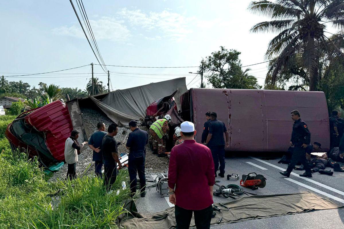 This handout photo taken and released by Perak's Fire and Rescue Department on May 13, 2025 shows rescuers searching for survivors after a lorry collided with a truck carrying members of the Malaysian paramilitary force Federal Reserve Unit (FRU) in Teluk Intan in Malaysia's Perak state. - AFPPIX