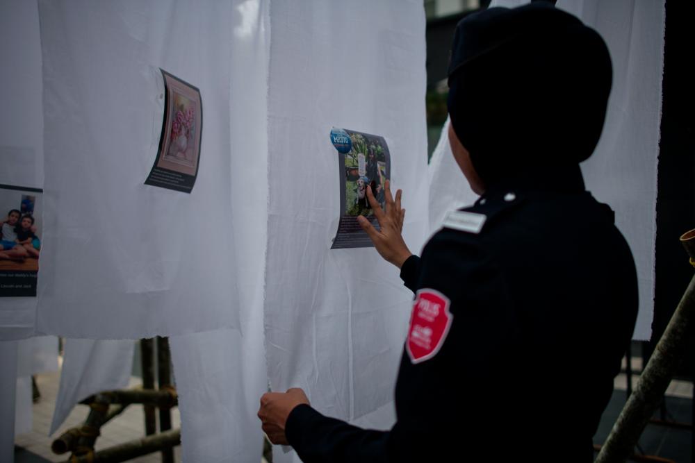 An auxiliary police officer touches a photograph with a message from loved ones to unaccounted for family members during a memorial event ahead of the fifth anniversary of the missing Malaysia Airlines flight MH370, in Kuala Lumpur on March 3, 2019. The Malaysia Airlines jet vanished on March 8, 2014 while en route from Kuala Lumpur to Beijing with 239 people onboard, most of them from China. — AFP