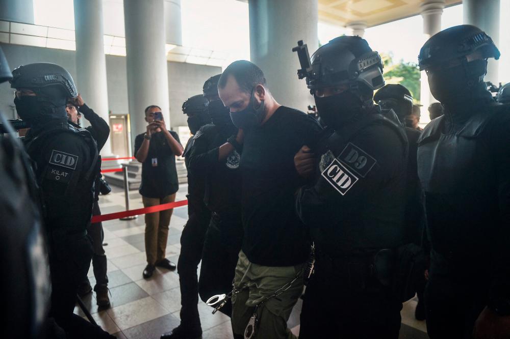 An Israeli man identified as Shalom Avitan (C) is escorted by Malaysian police upon his arrival at a court to face charges of possessing six handguns and 200 bullets in Kuala Lumpur on April 12, 2024. -AFPPIX