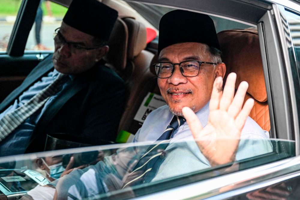 Malaysia opposition leader Anwar Ibrahim (R) waves as he arrives at the National Palace in Kuala Lumpur on November 22, 2022. AFPPIX
