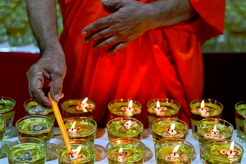 A Buddhist monk lights on oil lamp at the Buddhist Maha Vihara temple in Kuala Lumpur - AFPpix