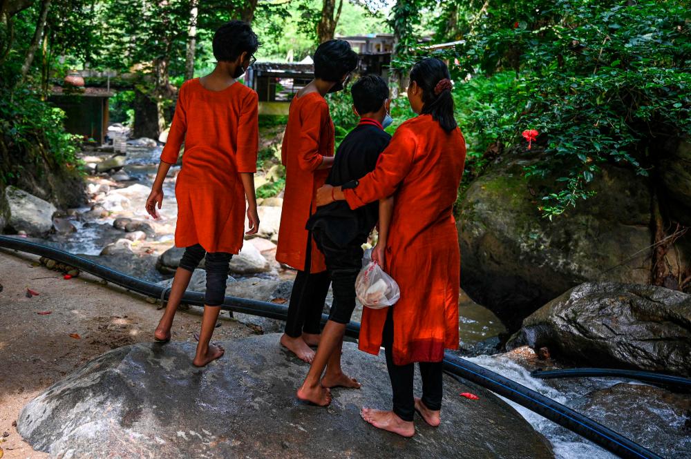 30 Mei 2022 - Loh Siew Hong (kanan) memeluk anaknya di sebelah anak-anaknya yang lain di tepi sungai di Gombak, negeri Selangor Malaysia. fotoAFP