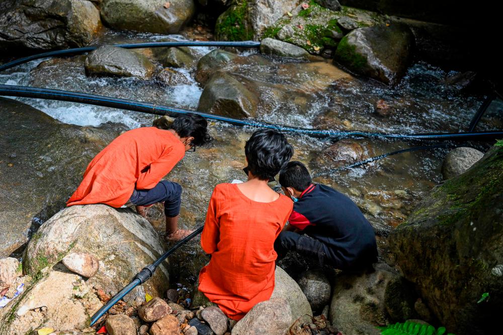 This picture taken on May 30, 2022 shows the children of Loh Siew Hong playing by a river in Gombak, Malaysia's Selangor state. AFPPIX