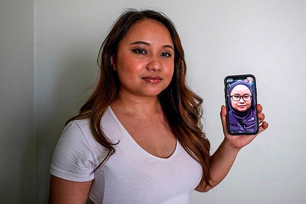This picture taken on Aug 17, 2020 shows Maryam Lee posing with a picture on a mobile phone of her wearing a headscarf in her parent’s home in Shah Alam, on the outskirts of Kuala Lumpur. — AFP