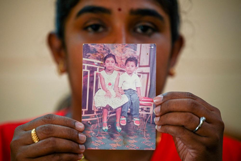 This picture taken on November 14, 2021 shows Sarmila Dharmalingam, elder sister of Nagaenthran K. Dharmalingam who has been sentenced to death for trafficking heroin into Singapore, displaying a photograph of herself and her brother when they were young while talking to Agence France-Presse (AFP) during an exclusive interview at her home in Tanjung Rambutan in Malaysia's Perak state. -AFPPix